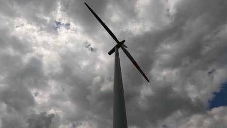 Low-angle-shot-of-a-wind-turbine,-rotating-and-creating-renewable-energy-on-a-cloudy-day,-4K