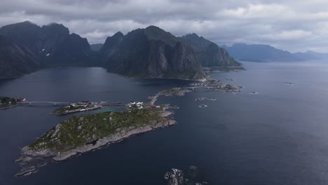 Aerial-View-of-Sakrisoy,-Olenilsoya,-and-Hamnoy-islands-surrounded-by-Reinefjorden-fjord-and-steep-mountains-cliffs-in-Moskenes-municipality-in-Nordland-county-in-Norway---side-dolly