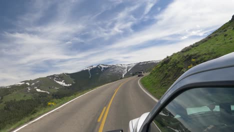 Camera-outside-of-white-truck-travelling-through-mountain-road-in-summer