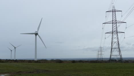 -Shot-of-wind-turbines-creating-renewable-energy-right-next-to-electricity-towers-and-power-lines,-4K