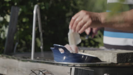 Medium-shot-of-male-adult-hands-washing-sliced-fish-outdoors-in-backyard,-pull-focus