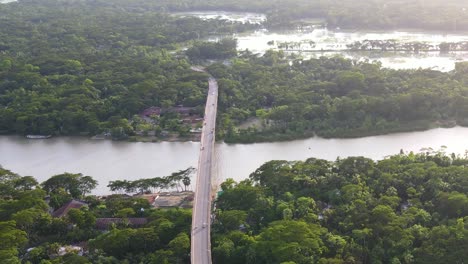 Aerial-dolly-shot-of-scenic-bridge-over-River-surrounded-by-tropical-vegetation,-Bangladesh