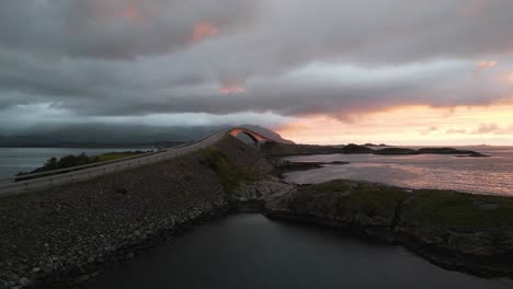 Moving-towards-the-Atlantic-Ocean-Road-Atlanterhavsveien-in-Norway-with-a-dramatic-sunset-and-clouds-covering-the-mountains
