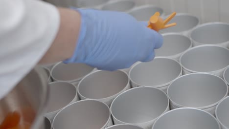 Worker-puts-small-spoons-into-different-cans-in-a-modern-clean-factory