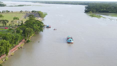 Aerial-view-towards-Riverbed-with-boats-cruise-near-forested-riverbank,-Bangladesh