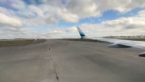 View-Of-Airplane-Wing-Running-On-The-Airport-Runway-Upon-Arrival-In-Seattle,-Washington