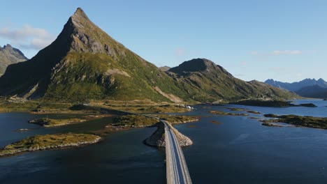Following-a-car-passing-the-lonely-Fredvang-road-bridge-in-Lofoten-Northern-Europe-with-view-towards-the-lonely-mountain-peak-between-summer-and-autumn