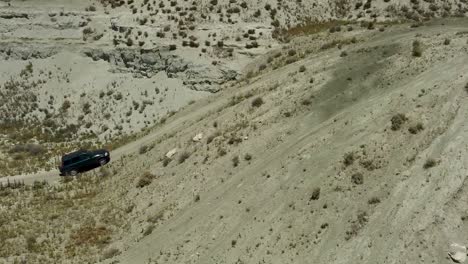Aerial-shot-focused-in-a-4x4-vehicle-triying-to-climb-a-steep-dirt-slope,-and-failing-in-the-attempt