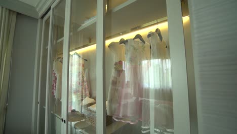 Girl-Fancy-Dress-Hanging-in-White-Glass-Door-Closet,-Close-Up