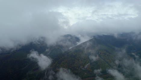 Un-Dron-Aéreo-Se-Disparó-Hacia-Adelante-Sobre-Nubes-Blancas-Que-Pasaban-Por-Encima-De-Una-Cordillera-Cubierta-De-Densa-Vegetación-Verde-Durante-El-Día