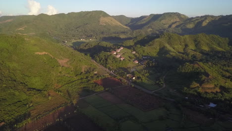 Aerial-descends-across-rice-field-toward-hilltop-jungle-villa,-Lombok
