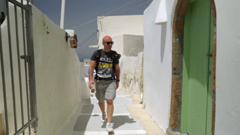 A-man-walks-down-an-alley-of-a-Greek-island-on-a-sunny-day