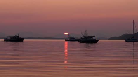 Boats-on-calm-ocean-water-during-red-smokey-sunset