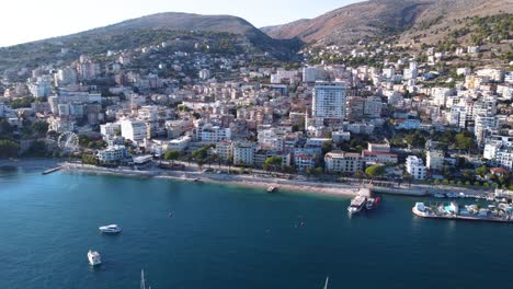 AERIAL-Slow-Approaching-Shot-of-Sarande,-Albania-by-the-Beautiful-Mediterranean-Sea