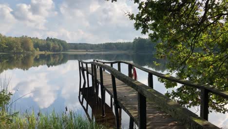Blick-Auf-Einen-Schönen,-Ruhigen-See,-Umgeben-Von-Bäumen-Mit-Holzplattform,-Schwenk