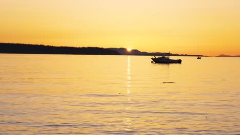 Wide-shot-of-small-boat-on-calm-ocean-during-golden-sunset