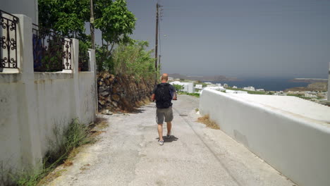 Following-a-man-walking-down-a-narrow-street-of-a-Greek-island-1