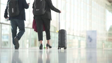 People-in-business-outfits-walking-with-luggage-in-a-bright-hall