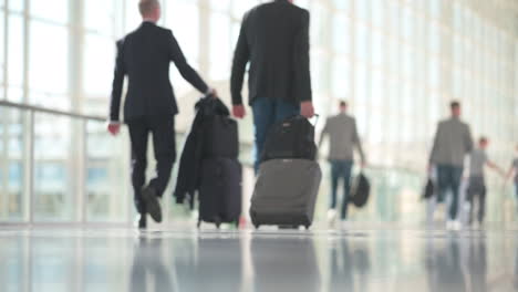 Woman-in-business-outfit-walking-in-slow-motion,-man-with-suitcases-in-the-background