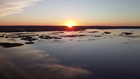 Kran-Drohnenansicht-Bei-Sonnenuntergang-über-Einem-See,-Feuchtgebiete-Mit-Einem-Fluss-Im-Hintergrund