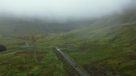 Aerial-view-of-a-car-in-a-road-in-the-middle-of-mountains-in-Ireland