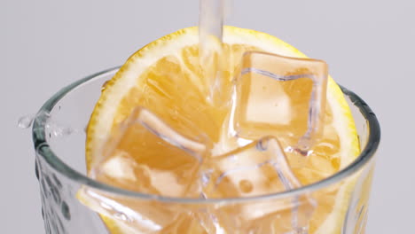 Cold-fresh-sparkling-water-pouring-into-a-glass-with-ice-and-lemon-slices-3