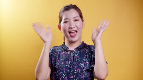 Kind-friendly-Asian-woman-charmingly-smiles-waving-her-hand-in-a-happy-greeting-welcome-or-goodbye