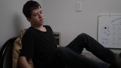 A-young-high-school-aged-teen-boy-sits-on-his-bed-looking-troubled-and-sad-as-he-looks-at-baseball-cards