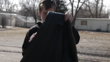 A-young-high-school-aged-teen-boy-walking-outside-puts-on-his-backpack-and-heads-to-school