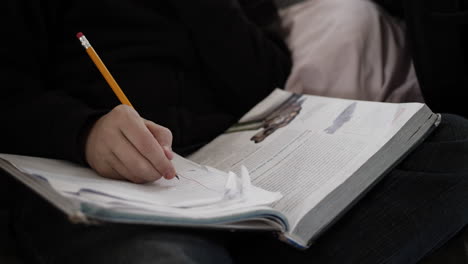 Closeup-of-a-young-man,-teenage-boy-doing-his-homework-with-a-pencil