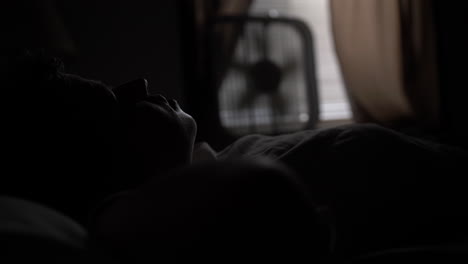 Silhouette-of-a-young-high-school-aged-teen-boy-lays-in-his-bed