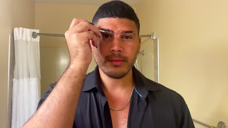 Gay-mixed-race-black-male-applying-brow-gel-makeup-in-bathroom,-LGBTQ-diversity