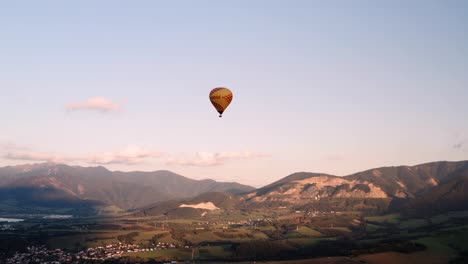 Yellow-hot-air-balloon-gliding-over-countryside-at-sunrise---high-angle-view