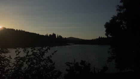 4k-Handheld-footage-looking-through-a-patch-of-bushes-out-onto-a-river-at-sunset-in-the-Pacific-Northwest,-USA,-in-summer