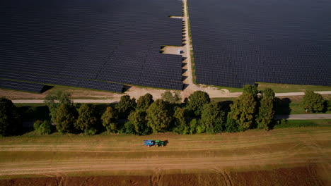 Luftaufnahme-Einer-Großen-Solarpanel-Farm-Mit-Vorbeifahrendem-Traktor