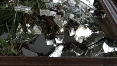 A-broken-and-shattered-mirror-lays-on-the-ground-with-reflective-shards-of-glass
