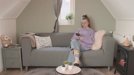 Girl-sitting-on-couch-with-her-phone,-Wide