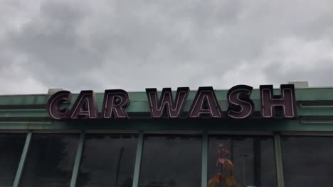A-handheld-shot-of-gloomy-skies-over-an-abandoned-neon-car-wash-sign