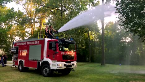 Deutsches-Feuerwehrauto,-Das-An-Einem-Heißen-Sommertag-Wasser-Für-Kinder-Und-Bäume-Sprüht-3