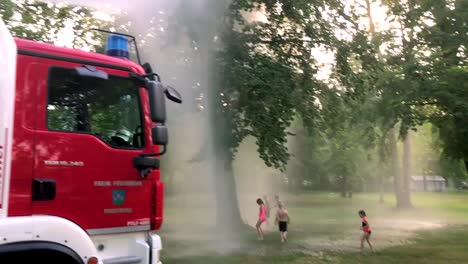 Deutsches-Feuerwehrauto,-Das-An-Einem-Heißen-Sommertag-Wasser-Für-Kinder-Und-Bäume-Sprüht-11