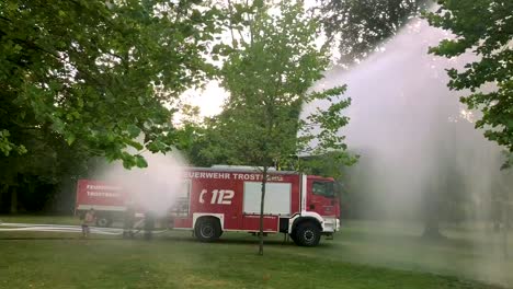 Deutsches-Feuerwehrauto,-Das-An-Einem-Heißen-Sommertag-Wasser-Für-Kinder-Und-Bäume-Sprüht-9