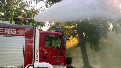 Deutsches-Feuerwehrauto,-Das-An-Einem-Heißen-Sommertag-Wasser-Für-Kinder-Und-Bäume-Sprüht-1