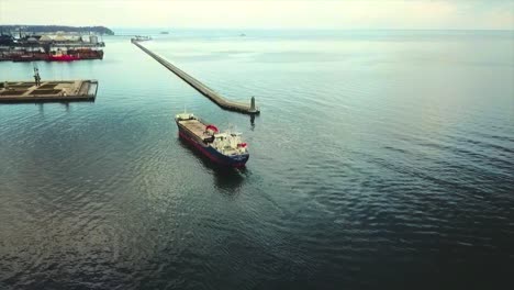 Drone-flying-and-following-big-cargo-ship-going-into-the-port
