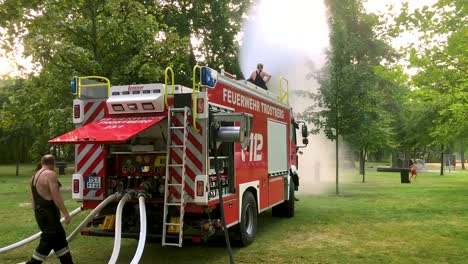 Deutsches-Feuerwehrauto,-Das-An-Einem-Heißen-Sommertag-Wasser-Für-Kinder-Und-Bäume-Sprüht-6