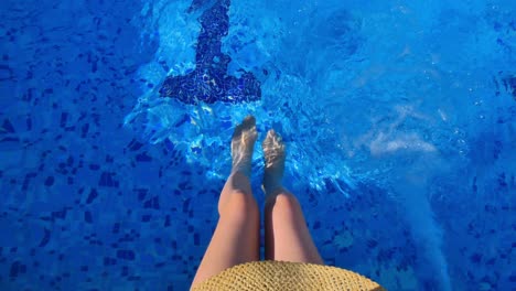 A-woman-sitting-at-the-edge-of-the-pool-in-a-summer-day