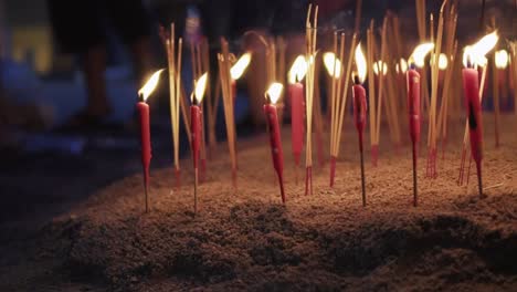 Panning-Shot-Of-Burning-Red-Candles-And-Incense-Sticks-On-the-Ground