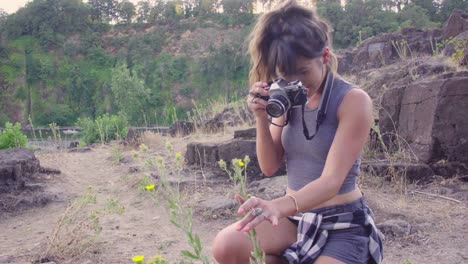 Cute-hipster-girl-taking-photos-of-flowers-on-a-film-camera