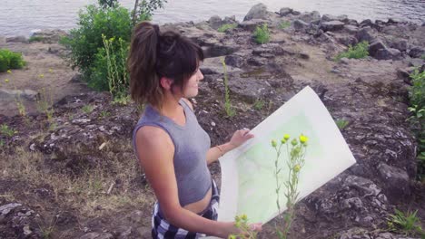 Cute-hipster-girl-opening-up-a-paper-map-and-exploring-the-park-she-is-in