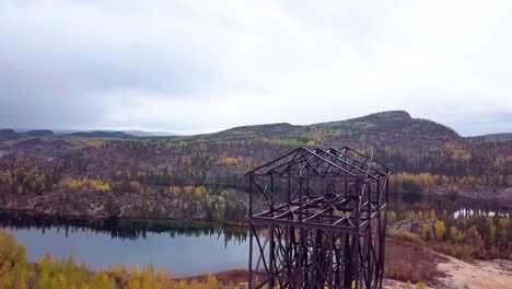 Slow-Motion-Aerial-downward-pedestal-of-an-abandoned-mine-headframe-in-the-boreal-forest-in-fall
