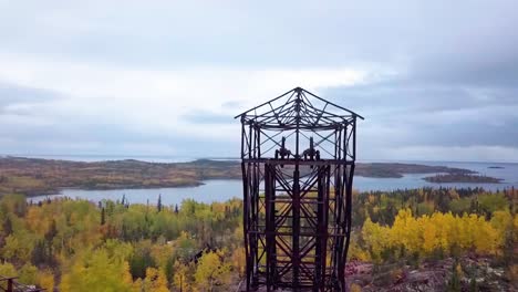 Aerial-Orbit-Panning-shot-of-an-abandoned-mine-headframe-in-the-boreal-forest-in-the-fall-with-a-lake-in-the-background